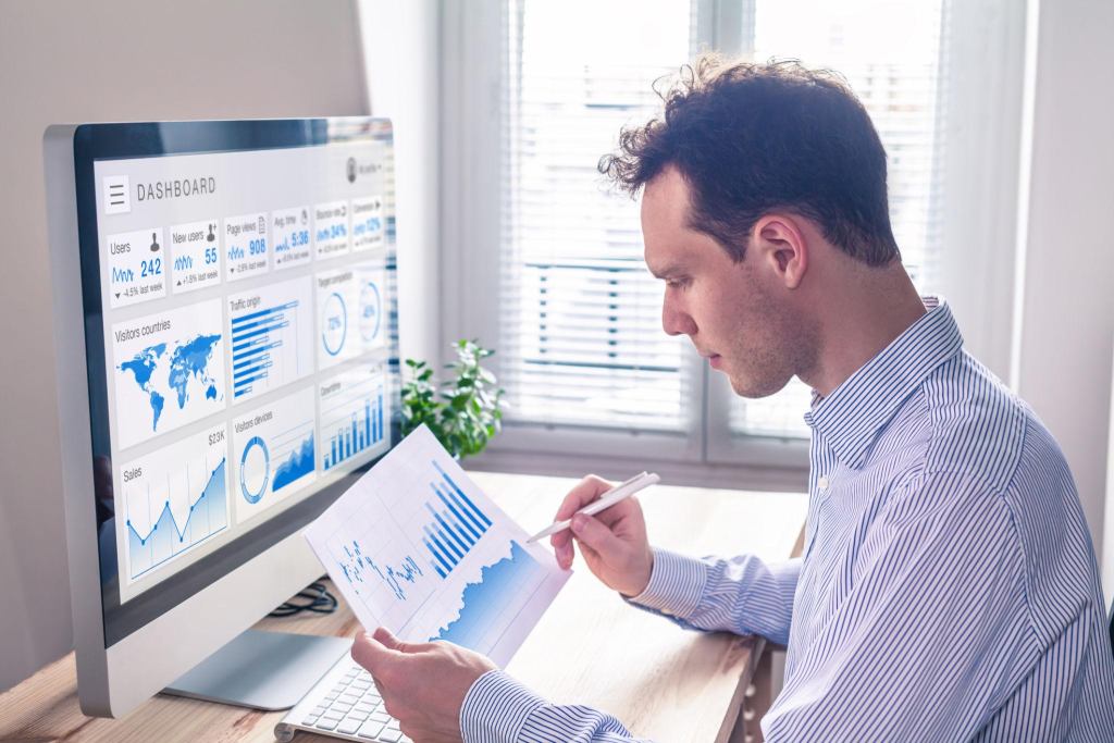 Digital marketing analytics technology with metrics and key performance indicators dashboard on computer screen, person analyzing data chart and advertisement campaign strategy in office