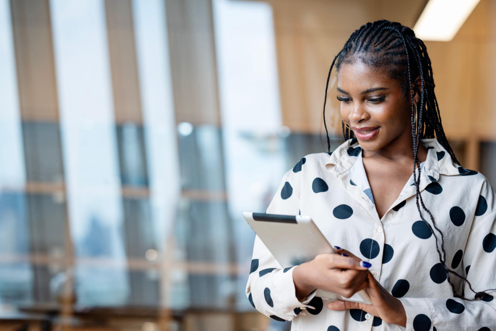 Using Digital Marketing in Your Business to Customer Reach Anywhere in the Purchasing Journey. Young female African-American Marketer using a tablet computer to review marketing plan in a b