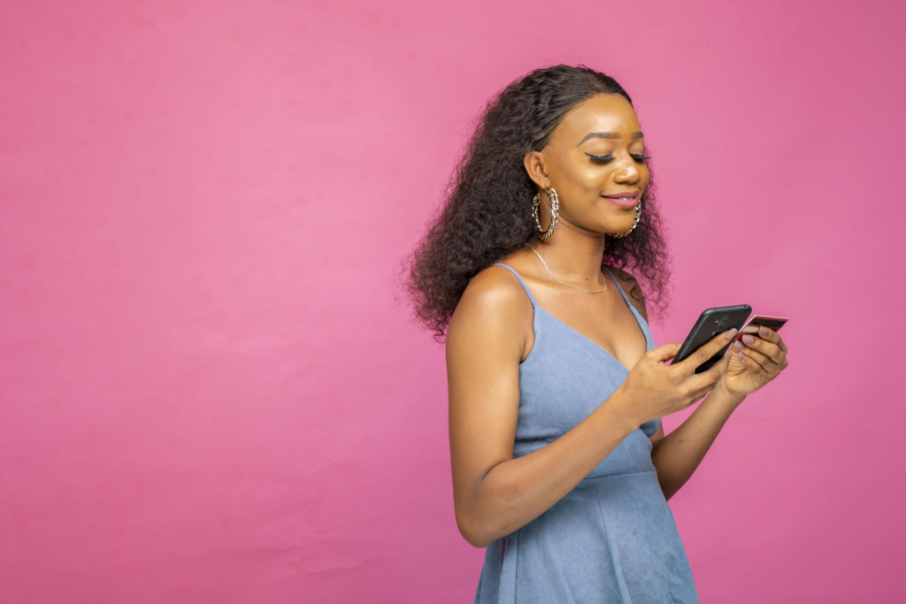 Young African female purchasing online using her smartphone and a credit card