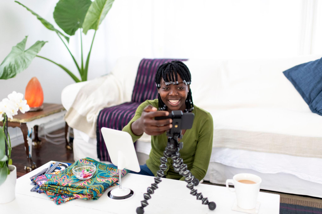 African influencer presses record on smart phone for vlog